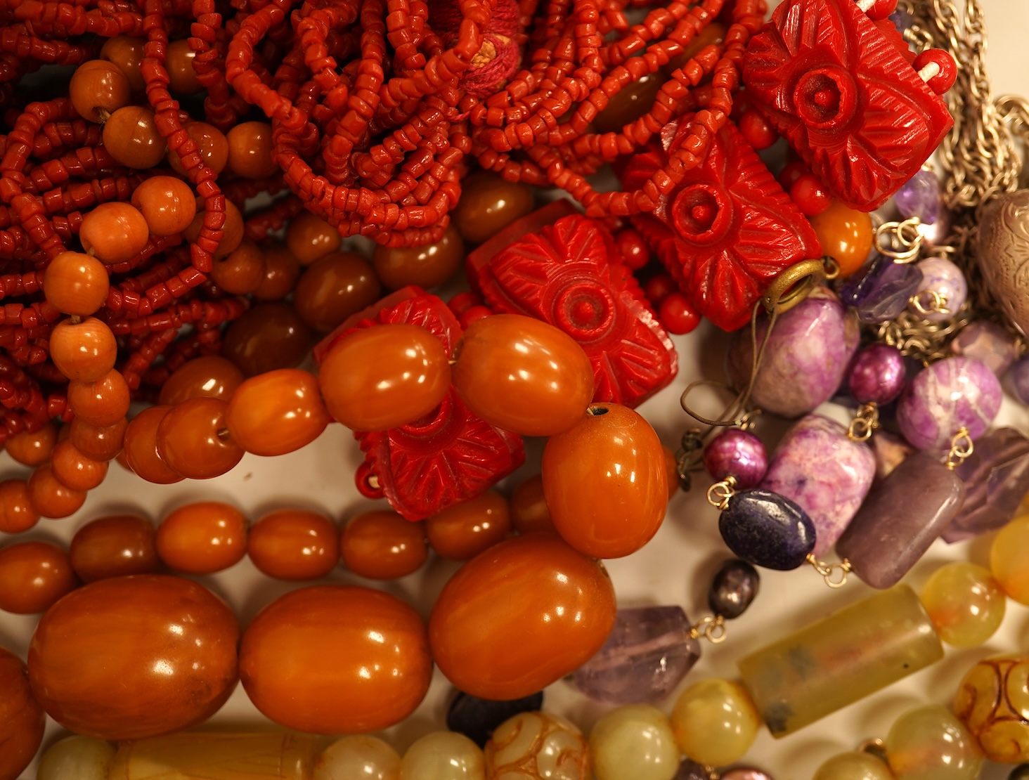 A small group of sundry jewellery including a simulated amber necklace and a multi strand coral bead necklace, etc.